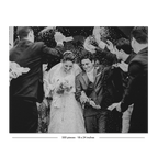Black and white wedding photograph showing a bride in a lace gown and groom in a suit being showered with confetti, surrounded by guests throwing paper bags. The photo is framed with a black border and small text at the bottom reading '200 places - 15 x 24 inches'.